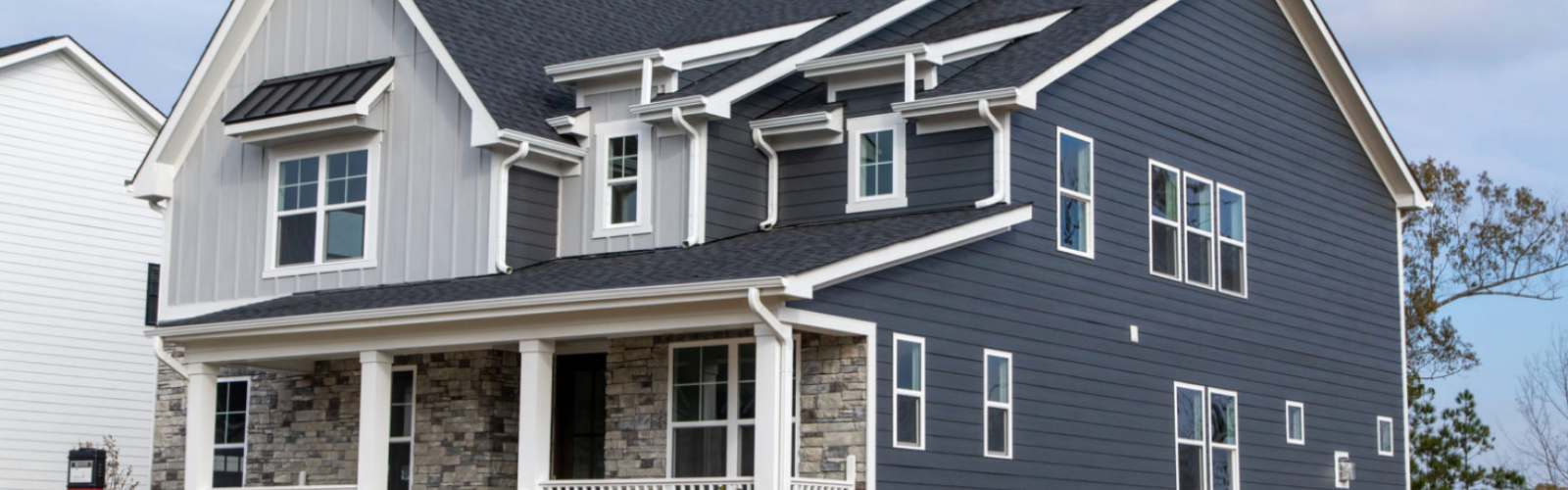 A two-story home featuring Allura fiber cement siding in both light and dark gray with stone accents and white detailing.