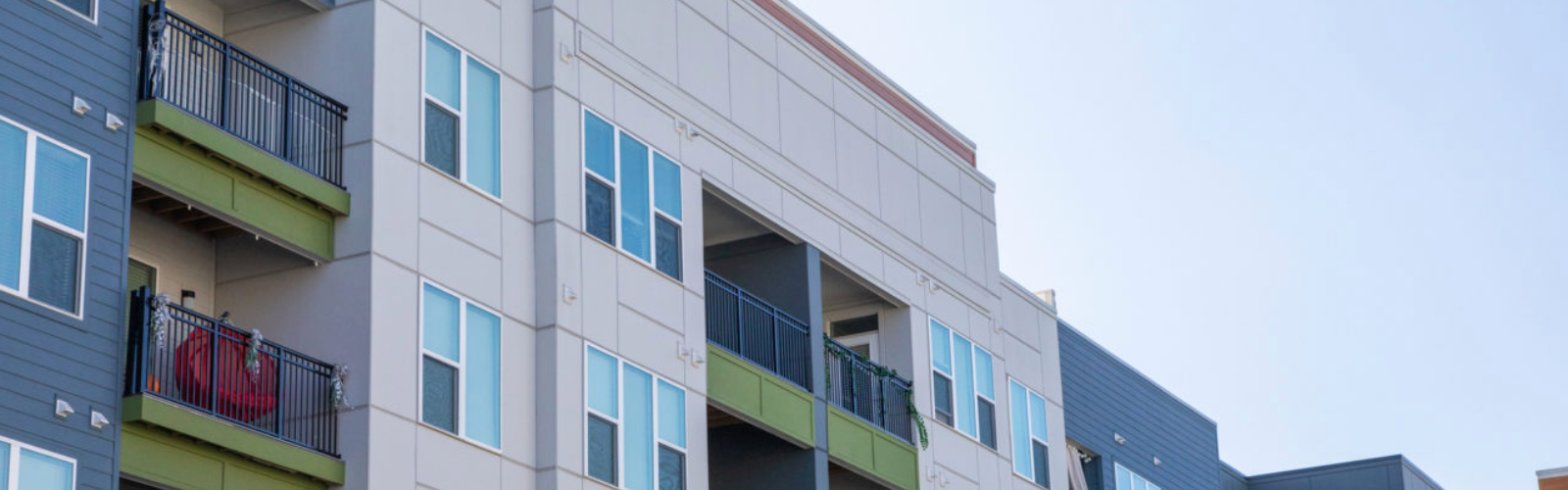 A commercial building features fiber cement siding in shades of olive green, gray and cream.