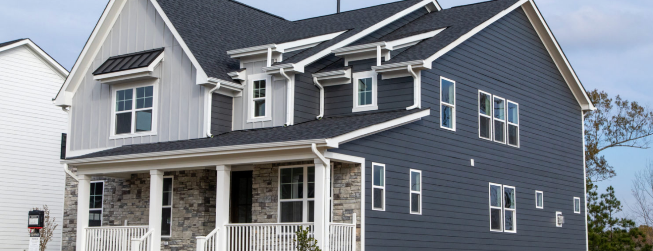 A two-story home featuring Allura fiber cement siding in both light and dark gray with stone accents and white detailing.