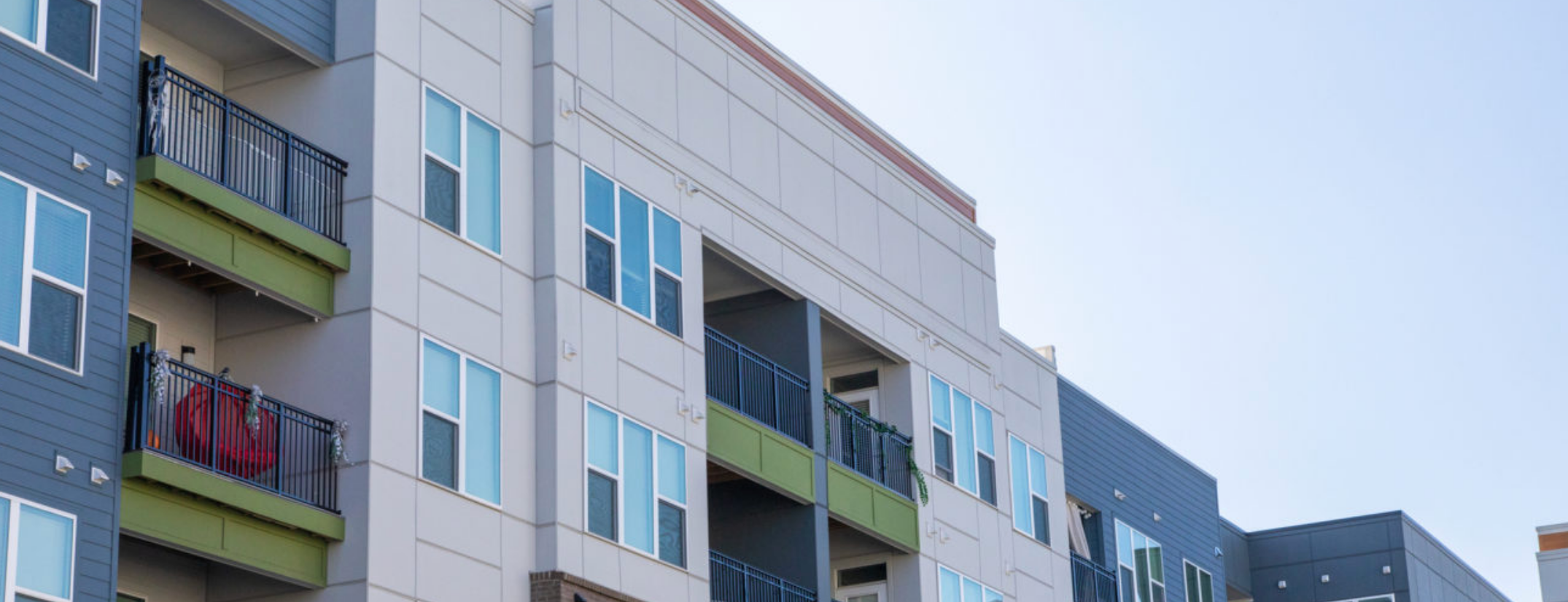 A commercial building features fiber cement siding in shades of olive green, gray and cream.