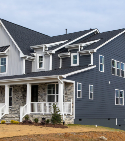 A two-story home featuring Allura fiber cement siding in both light and dark gray with stone accents and white detailing.