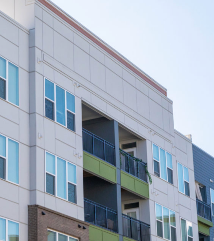 A commercial building features fiber cement siding in shades of olive green, gray and cream.