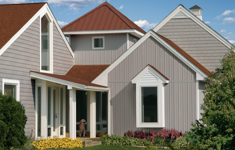 A modern grey fiber cement home with red-brown roofing and white trim.