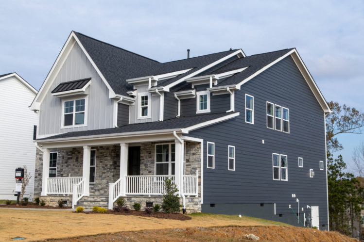 A two-story home featuring Allura fiber cement siding in both light and dark gray with stone accents and white detailing.