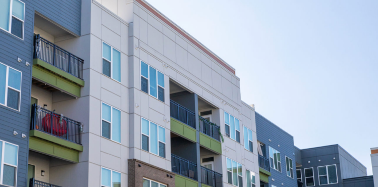 A commercial building features fiber cement siding in shades of olive green, gray and cream.