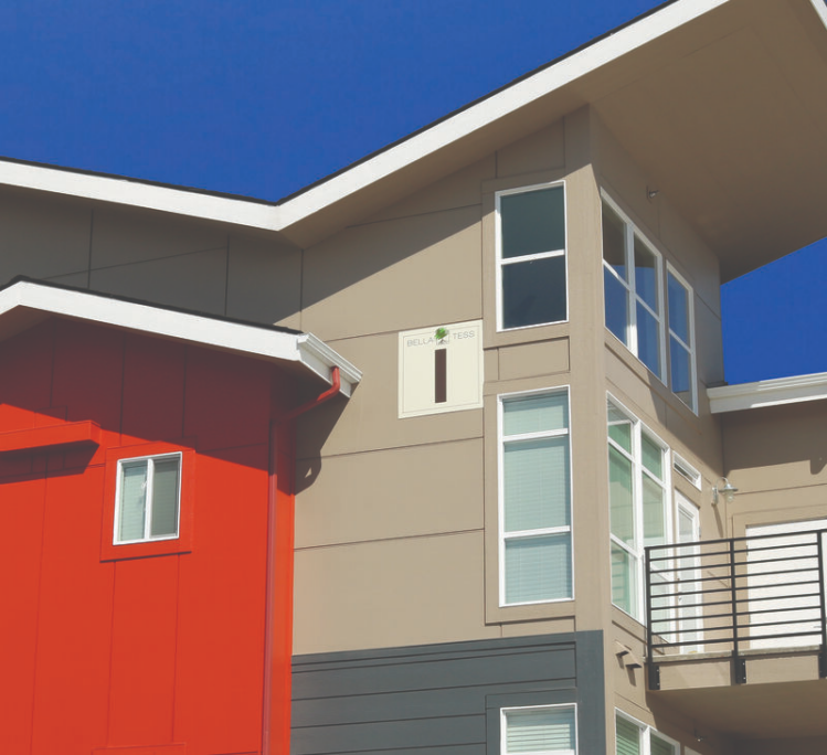 A commercial building features fiber cement siding in shades of tan, gray and red.