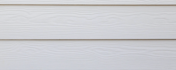 Close-up of white fiber cement siding on the side of a home.